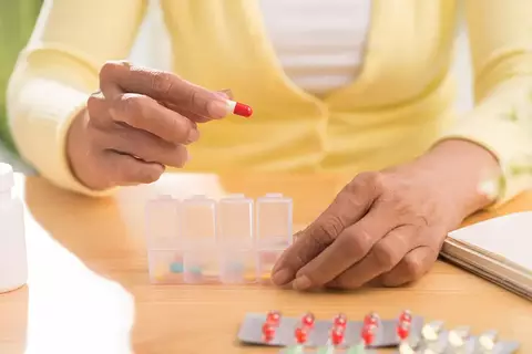 Vrouw die pillen in een doosje steekt